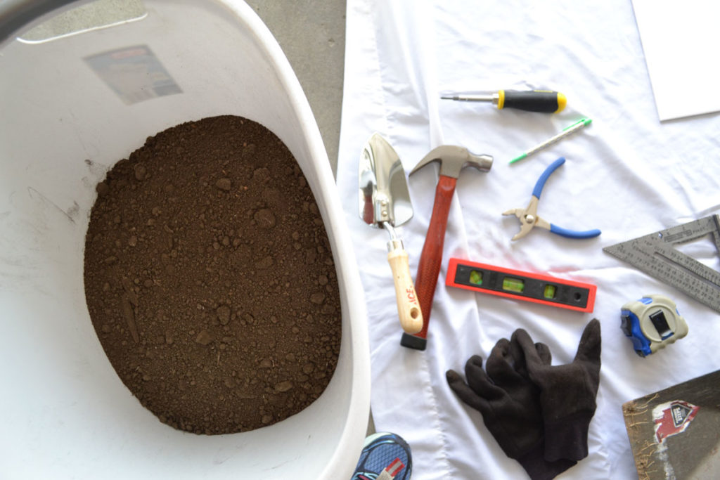 tools, dirt, and poster board supplies to create lettering project